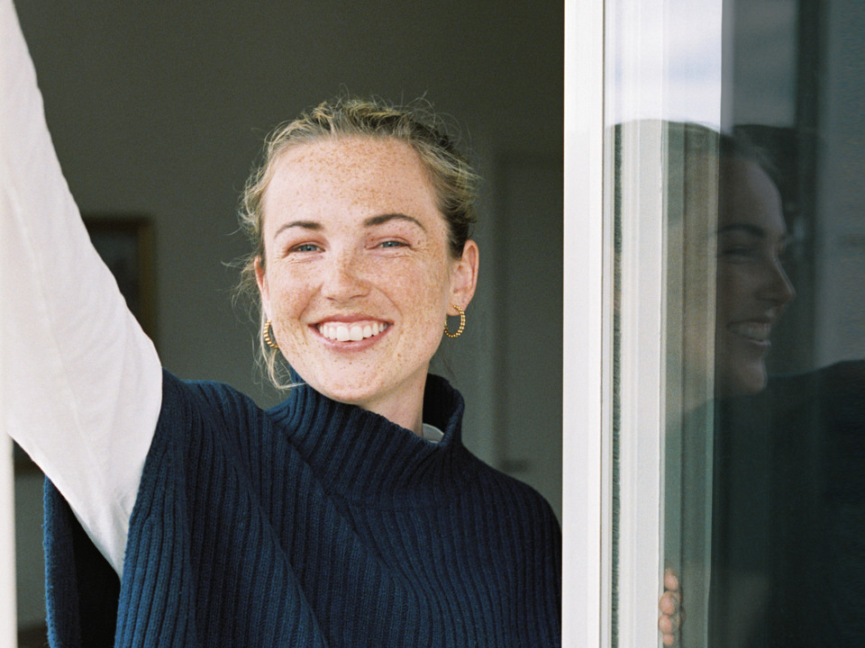 Ung kvinna ler mot betraktaren i ett fönster