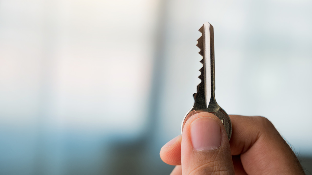 Närbild på en hand som håller upp en nyckel.