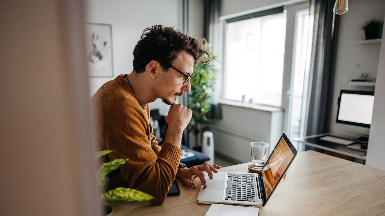 man sitter med en laptop och ett anteckningsblock