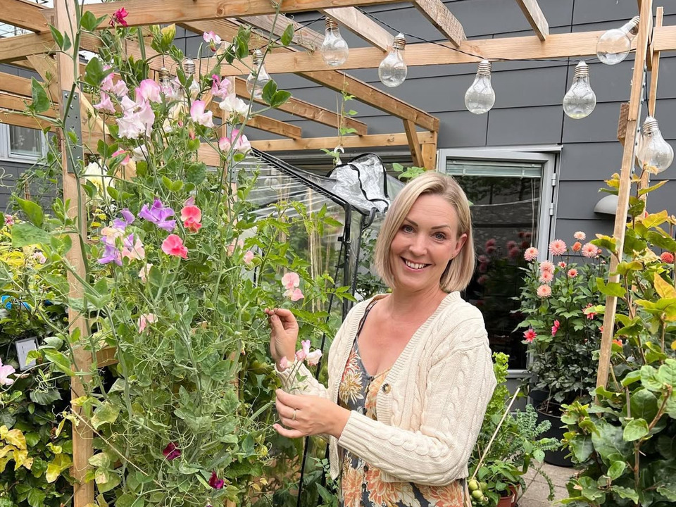 En kvinna står på en uteplats fylld med blommor